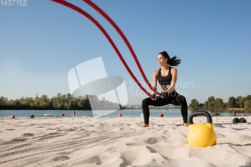 Image of Young healthy female athlete doing workout at the beach