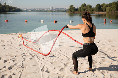 Image of Young healthy female athlete doing workout at the beach