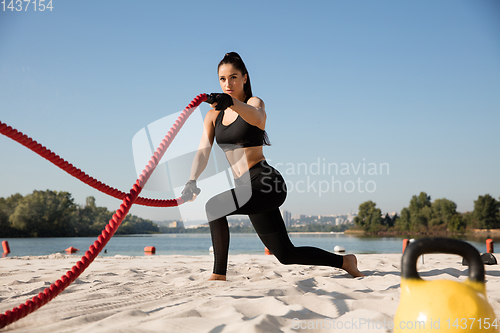 Image of Young healthy female athlete doing workout at the beach