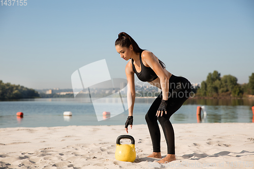 Image of Young healthy female athlete doing workout at the beach