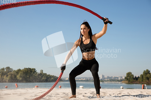 Image of Young healthy female athlete doing workout at the beach