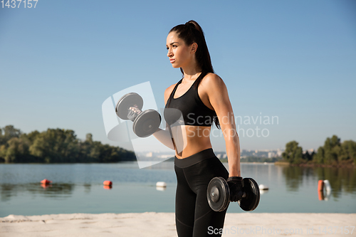 Image of Young healthy female athlete doing workout at the beach