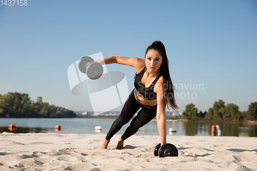 Image of Young healthy female athlete doing workout at the beach