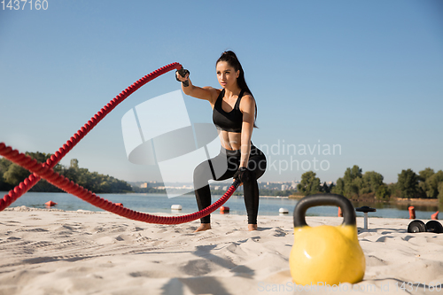 Image of Young healthy female athlete doing workout at the beach