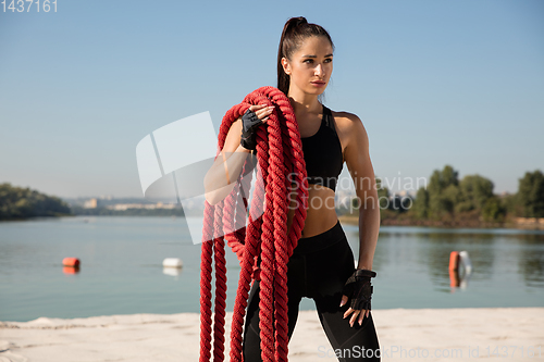 Image of Young healthy female athlete doing workout at the beach