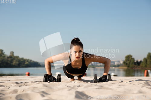 Image of Young healthy female athlete doing workout at the beach