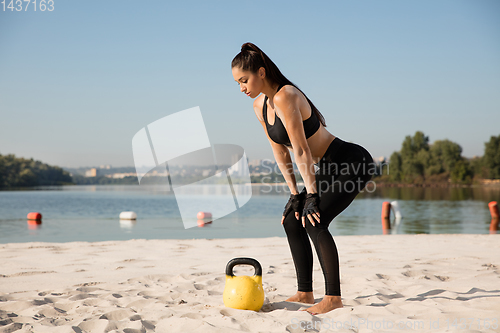 Image of Young healthy female athlete doing workout at the beach