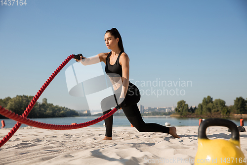 Image of Young healthy female athlete doing workout at the beach