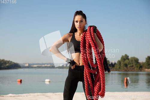 Image of Young healthy female athlete doing workout at the beach