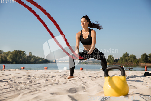 Image of Young healthy female athlete doing workout at the beach