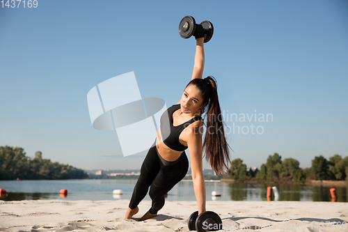 Image of Young healthy female athlete doing workout at the beach