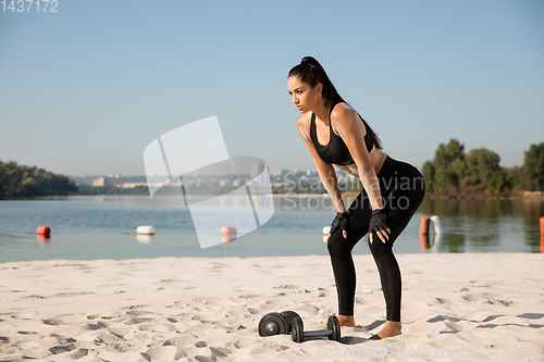 Image of Young healthy female athlete doing workout at the beach