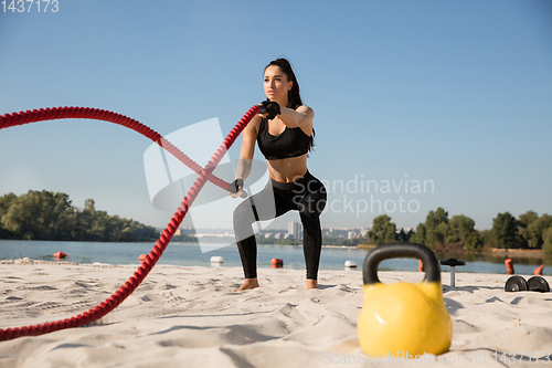 Image of Young healthy female athlete doing workout at the beach