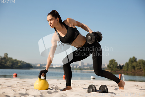 Image of Young healthy female athlete doing workout at the beach