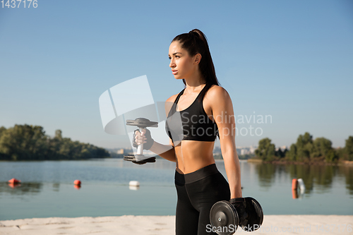 Image of Young healthy female athlete doing workout at the beach