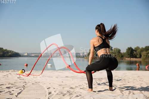 Image of Young healthy female athlete doing workout at the beach