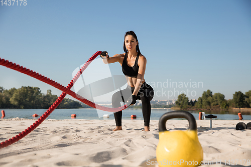 Image of Young healthy female athlete doing workout at the beach