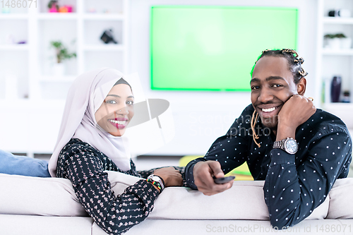 Image of African Couple Sitting On Sofa Watching TV Together