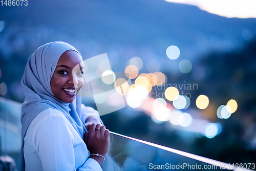 Image of African  modern Muslim woman in night at balcony