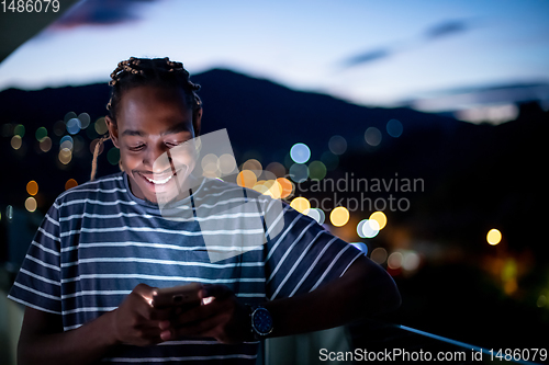 Image of Young  Afro man on  street at night using phone