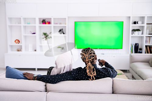 Image of African Couple Sitting On Sofa Watching TV Together