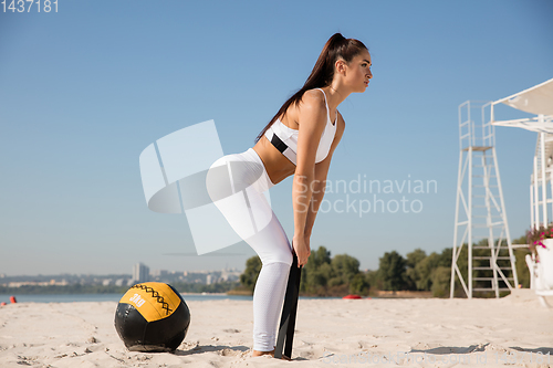 Image of Young healthy female athlete doing workout at the beach