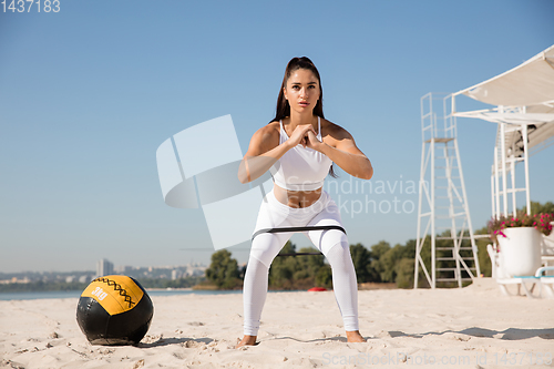 Image of Young healthy female athlete doing workout at the beach