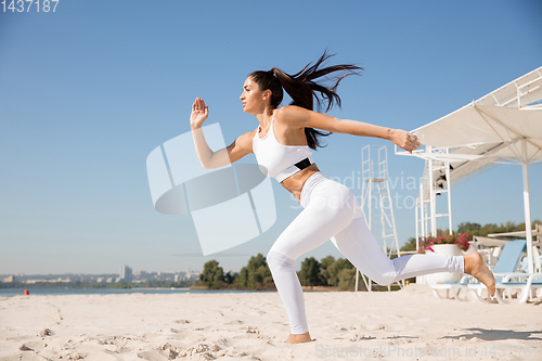 Image of Young healthy female athlete doing workout at the beach