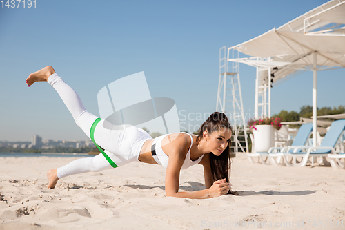Image of Young healthy female athlete doing workout at the beach