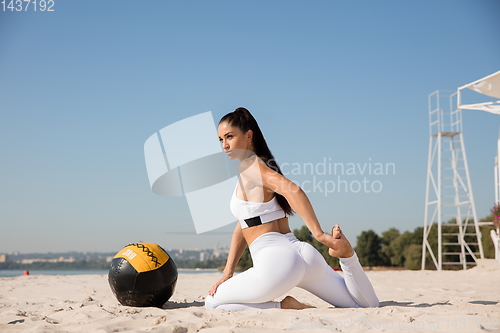 Image of Young healthy female athlete doing workout at the beach