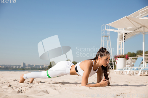 Image of Young healthy female athlete doing workout at the beach