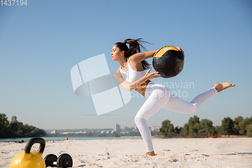 Image of Young healthy female athlete doing workout at the beach