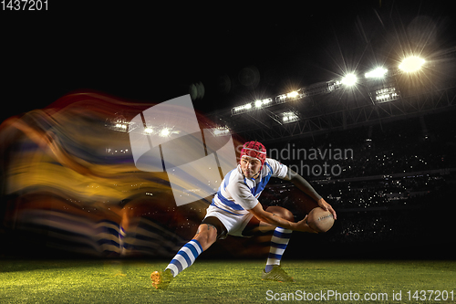 Image of One caucasian man playing rugby on the stadium in mixed light