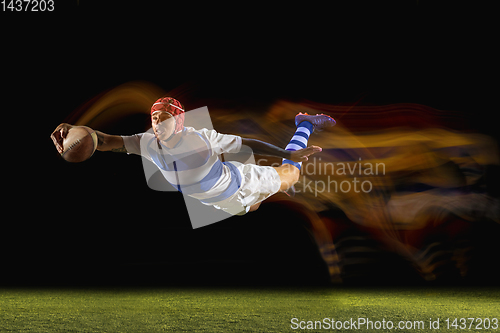 Image of One caucasian man playing rugby on the stadium in mixed light