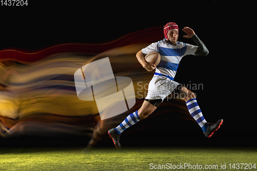 Image of One caucasian man playing rugby on the stadium in mixed light