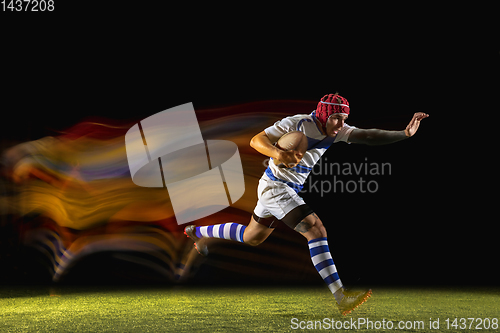 Image of One caucasian man playing rugby on the stadium in mixed light