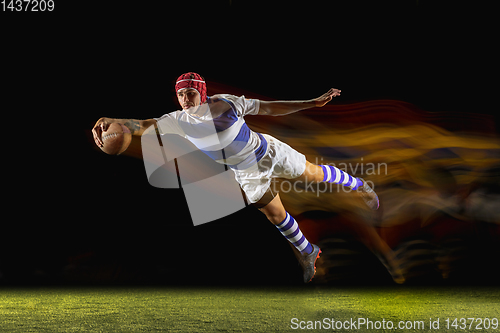 Image of One caucasian man playing rugby on the stadium in mixed light