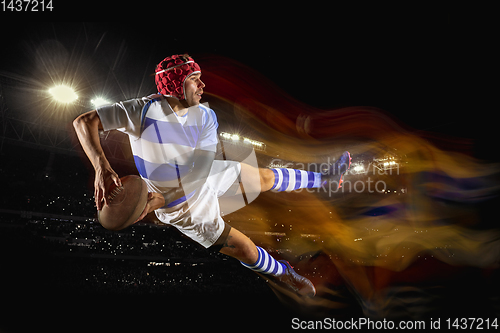 Image of One caucasian man playing rugby on the stadium in mixed light