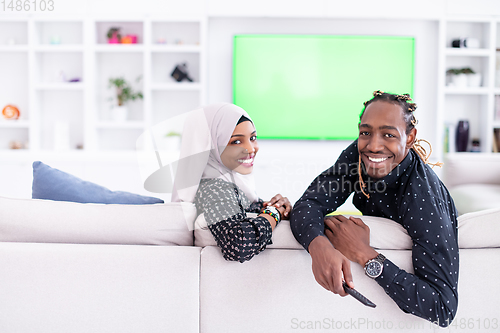 Image of African Couple Sitting On Sofa Watching TV Together