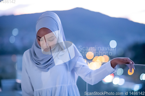 Image of African  modern Muslim woman in night at balcony