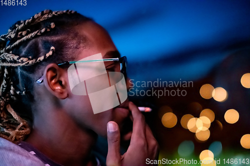 Image of african american man smoking cigarette  at night