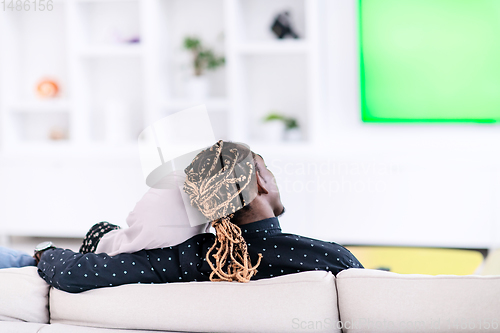 Image of African Couple Sitting On Sofa Watching TV Together