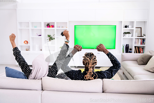 Image of African Couple Sitting On Sofa Watching TV Together