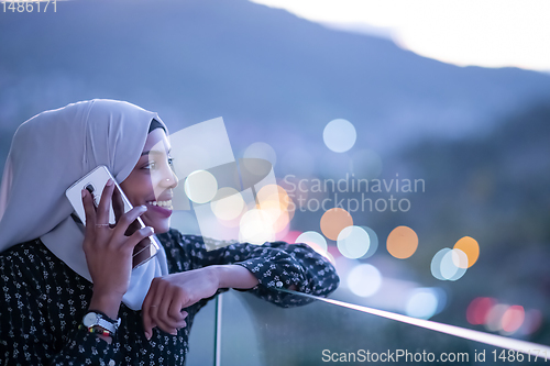 Image of Young Muslim woman on  street at night using phone