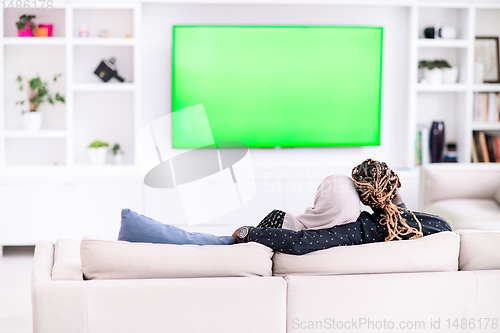 Image of African Couple Sitting On Sofa Watching TV Together