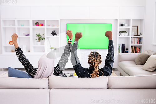 Image of African Couple Sitting On Sofa Watching TV Together
