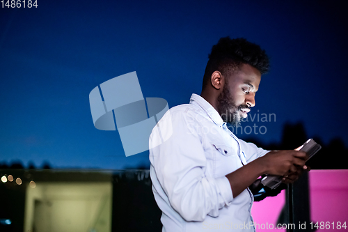 Image of Young  Afro man on street at night using tablet computer