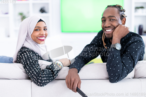 Image of African Couple Sitting On Sofa Watching TV Together