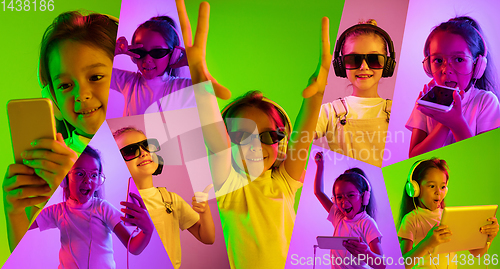 Image of Little girl with gadgets on multicolored background in neon ligh