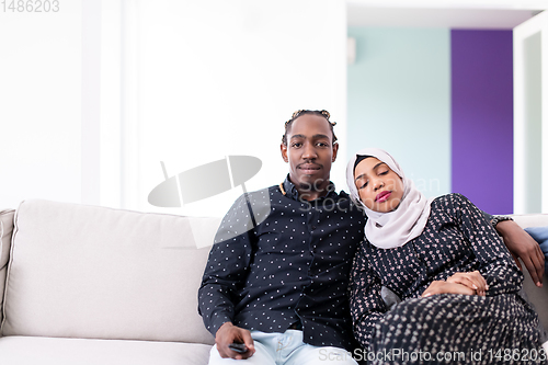 Image of African Couple Sitting On Sofa Watching TV Together